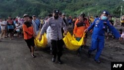 Sejumlah anggota SAR mengevakuasi jenazah anggota kelompok masyarakat yang tewas terseret ombak saat melakukan ritual di Pantai Payangan, Jember, Jawa Timur, 13 Februari 2022. (Foto: Sebastian Revan Junardi/AFP)