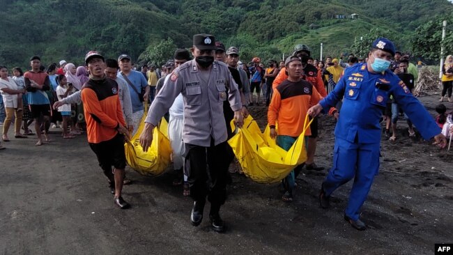 Sejumlah anggota SAR mengevakuasi jenazah anggota kelompok masyarakat yang tewas terseret ombak saat melakukan ritual di Pantai Payangan, Jember, Jawa Timur, 13 Februari 2022. (Foto: Sebastian Revan Junardi/AFP)
