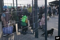 People wait to cross from pro-Russian separatists' controlled territory to Ukrainian government-controlled areas in Stanytsia Luhanska, the only crossing point open daily, in the Luhansk region, eastern Ukraine, Tuesday, Feb. 22, 2022. (AP Photo/Vadim Ghirda)