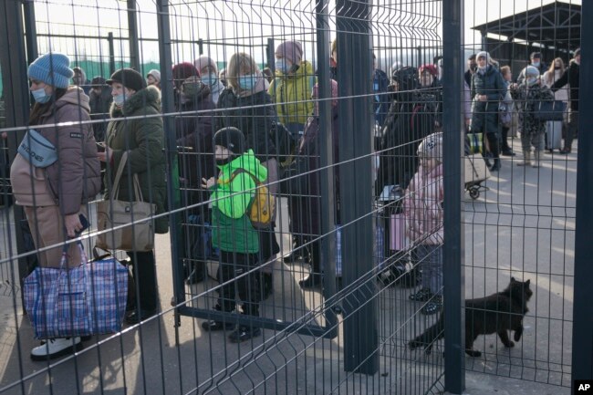 People wait to cross from pro-Russian separatists' controlled territory to Ukrainian government-controlled areas in Stanytsia Luhanska, the only crossing point open daily, in the Luhansk region, eastern Ukraine, Tuesday, Feb. 22, 2022. (AP Photo/Vadim Ghirda)