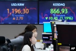 Currency traders watch monitors at the foreign exchange dealing room of the KEB Hana Bank headquarters in Seoul, South Korea, Thursday, Feb. 24, 2022. Asian stock markets followed Wall Street lower Thursday as anxiety about a possible Russian invasion of Ukraine rose. (AP Photo/Ahn Young-joon)