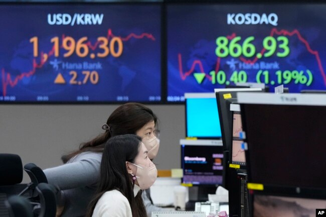 Currency traders watch monitors at the foreign exchange dealing room of the KEB Hana Bank headquarters in Seoul, South Korea, Thursday, Feb. 24, 2022. Asian stock markets followed Wall Street lower Thursday as anxiety about a possible Russian invasion of Ukraine rose. (AP Photo/Ahn Young-joon)