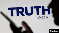 El logotipo de la red social Truth se muestra detrás de una mujer que sostiene un teléfono inteligente en esta ilustración tomada el 21 de febrero de 2022.