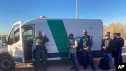 FILE - A Border Patrol agent fills out paperwork for migrants who surrendered in Yuma, Ariz., Feb. 5, 2022, after crossing the border illegally from Los Algodones, Mexico.