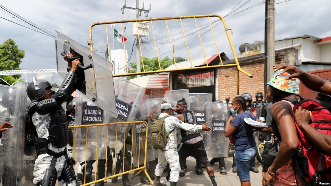 Para migran melemparkan pagar ke arah anggota Garda Nasional dalam aksi protes di luar kantor National Migration Institute (INM) di Tapachula, Meksiko 22 Februari 2022. (REUTERS/Jacob Garcia)