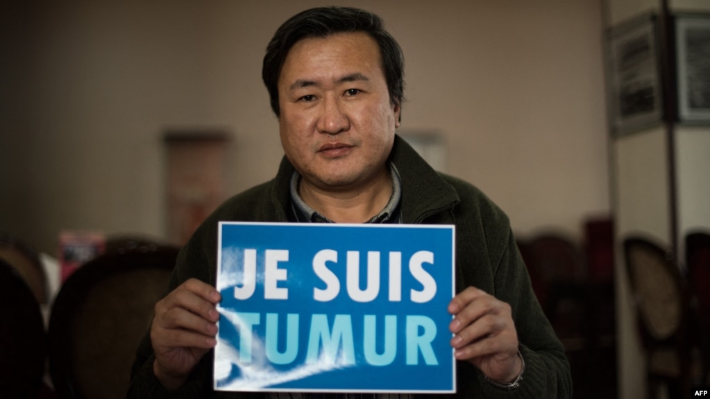 资料照片：2015年2月9日，蒙古活动人士蒙赫巴亚尔·楚鲁恩道尔吉（Munkhbayar Chuluundorj)在乌兰巴托接受采访时举着'我是特木尔'的法语标语牌。据报道，中国内蒙古牧民特木尔同年为抗议开发商和矿主侵占土地而自杀，这类事件得到了蒙古国活动人士的关注。(photo:VOA)