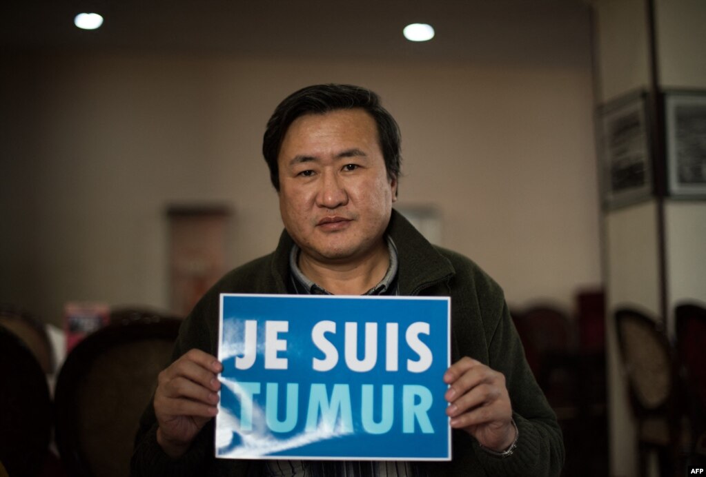 资料照片：2015年2月9日，蒙古活动人士蒙赫巴亚尔·楚鲁恩道尔吉在乌兰巴托接受采访时举着'我是特木尔'的法文标语牌。据报道，中国内蒙古牧民特木尔同年为抗议开发商和矿主侵占土地而自杀，这类事件得到蒙古国活动人士的关注。(photo:VOA)