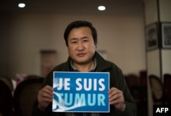 资料照片：2015年2月9日，蒙古活动人士蒙赫巴亚尔·楚鲁恩道尔吉在乌兰巴托接受采访时举着"我是特木尔"的法文标语牌。据报道，中国内蒙古牧民特木尔同年为抗议开发商和矿主侵占土地而自杀，这类事件得到蒙古国活动人士的关注。