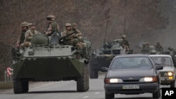 Militares ucranianos sentados encima de vehículos blindados de transporte de personal que conducen por una carretera en la región de Donetsk, en el este de Ucrania, el 24 de febrero de 2022.