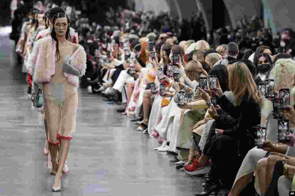 Bella Hadid, front, and other models wear creations by the Fendi Fall/Winter 2022-2023 fashion collection as guests record the show on their cell phones during the Fashion Week in Milan, Italy.