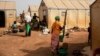 FILE - Displaced women prepare food at Kaya camp, some 100 kilometers north of Ouagadougou, Burkina Faso, Feb. 8, 2021.