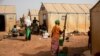 FILE - Displaced women prepare food at Kaya camp, some 100 kilometers north of Ouagadougou, Burkina Faso, Feb. 8, 2021. 