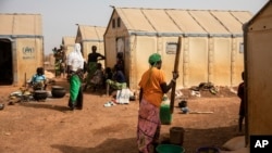 FILE - Displaced women prepare food at Kaya camp, some 100 kilometers north of Ouagadougou, Burkina Faso, Feb. 8, 2021. 