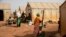 FILE - Displaced women prepare food at Kaya camp, some 100 kilometers north of Ouagadougou, Burkina Faso, Feb. 8, 2021. 