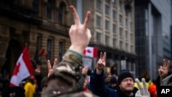 Protesters give peace signs in solidarity at a rally against COVID-19 restrictions outside Canada’s parliament building in Ottawa, Feb. 17, 2022.