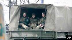 Ukrainian soldiers ride in a military vehicle in Mariupol, Ukraine, Feb. 24, 2022. 