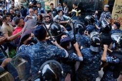 Anti-government protesters clash with riot police in front of the Ministry of Economy in downtown Beirut, Lebanon, Monday, May 11, 2020.