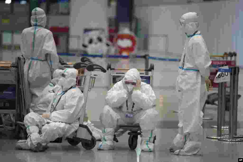 Olympic workers in protective clothing take a rest after helping travelers at Beijing Capital International airport after the 2022 Winter Olympics in Beijing, China.