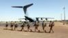 Des soldats français de l'opération Barkhane passant devant un Airbus A-400 M Atlas de l'armée de l'air française à la base militaire française de Tombouctou, au Mali, le 5 décembre 2021.