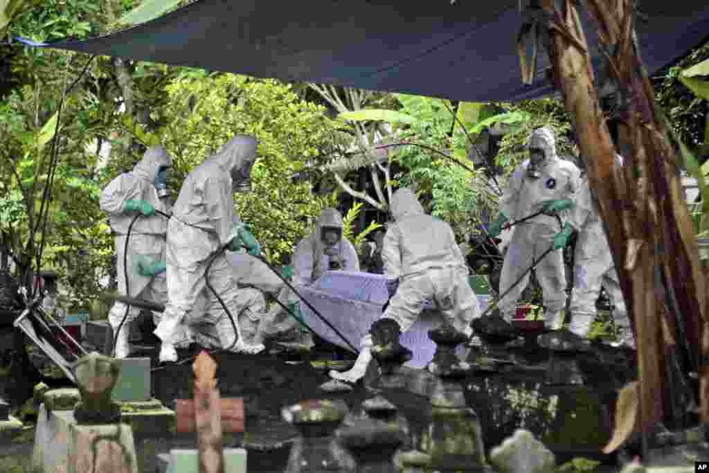 Workers in protective suits bury a COVID-19 victim during a funeral at a cemetery in Yogyakarta, Indonesia.