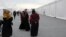 Afghan refugees walk alongside temporary housing in Liberty Village at Joint Base McGuire-Dix-Lakehurst in Trenton, New Jersey, Dec. 2, 2021. The U.S. government now plans to consolidate sites like this into one in northern Virginia. 