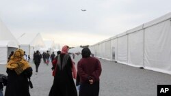 Afghan refugees walk alongside temporary housing in Liberty Village at Joint Base McGuire-Dix-Lakehurst in Trenton, New Jersey, Dec. 2, 2021.