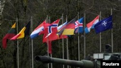 На фото: Прапори країн НАТО під час візиту міністерки оборони Крістіне Ламбрехт на військову базу у Литві, 22 лютого 2022