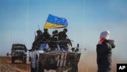 2022年 2月23日，一名妇女走过一张巨幅照片，这幅照片纪念乌克兰军队和亲俄分离主义武装在乌克兰东部卢甘斯克地区的西维耶罗顿涅茨克爆发的冲突中丧生的人。（美联社）