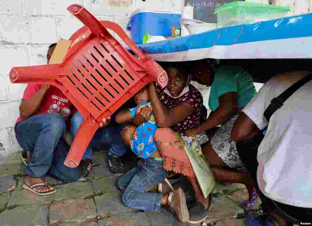 Migrants use a chair to protect themselves from rocks during a protest by migrants to demand speedy processing of humanitarian visas to continue on their way to the United States, outside the office of the National Migration Institute (INM) in Tapachula, Mexico, Feb. 22, 2022.