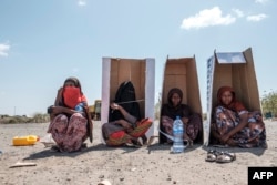 FILE - Displaced women sit under UNHCR-branded cardboard boxes as they wait to be registered by authorities in the city of Semera, Afar region, Ethiopia, Feb. 14, 2022.