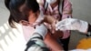 A young girl held by her mother pushes a shaft of a needle as she receives the first dose of Sinovac's COVID-19 vaccine at a health center outside Phnom Penh, Cambodia on Wednesday, Feb. 23, 2022. (AP Photo/Heng Sinith)