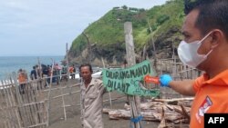 Polisi menggelar rekonstruksi insiden yang menewaskan sepuluh orang ketika menjalankan sebuah ritual di Pantai Payangan, Jember, Jawa Timur, 13 Februari 2022. (Foto: Sebastian Revan Junardi/AFP)
