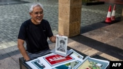 FILE - Political cartoonist Wong Kei-kwan displays some of his work in Hong Kong, June 20, 2020.