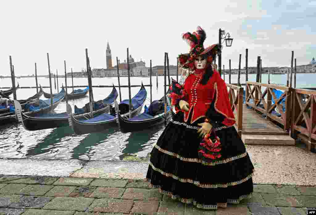 A masked reveler wearing a traditional carnival costume poses on St Mark Square, Venice, Italy, during the annual carnival.