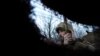 A Ukrainian service member listens to artillery shots standing in a trench on a position at the line of separation between Ukraine-held territory and rebel-held territory near Zolote, Ukraine, Feb. 19, 2022. 