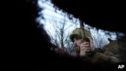 A Ukrainian service member listens to artillery shots standing in a trench on a position at the line of separation between Ukraine-held territory and rebel-held territory near Zolote, Ukraine, Feb. 19, 2022. 