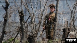 (FILE) A North Korean prison policewoman stands guard behind fences at a jail on the banks of Yalu River near the Chongsong county of North Korea, opposite the Chinese border city of Dandong, May 8, 2011. Picture taken May 8, 2011.