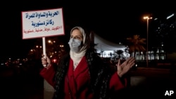 Mashael al-Shuwaihan, who sits on the board of Kuwait's Women's Cultural Society, speaks during an interview, at a protest outside Kuwait's National Assembly, in Kuwait City, Feb. 7, 2022. Her placard reads: "Freedom and equality for women are constitutional pillars.'