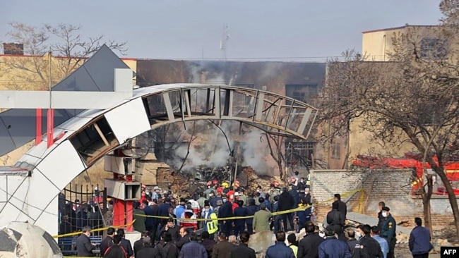A handout picture provided by the news agency TASNIM on February 21, 2022 shows residents gathering at the crash site of a fighter jet in a residential area of the northwestern city of Tabriz.