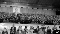 FILE - Then U.S. President Richard Nixon and then China's Premier Zhou Enlai join the applause at a gymnastic show in Beijing on Feb. 23, 1972 as they stand in the official box under a capacity crowd with a portrait of Chairman Mao Zedong above.