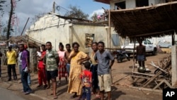 Des personnes se tiennent devant des maisons en ruine à Mananjary, Madagascar, le 10 février 2022.