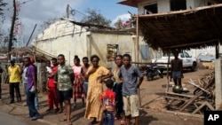 FILE - People outside ruined homes in Mananjary, Madagascar, Feb. 10, 2022. The island of Madagascar off the east coast of Africa is bracing for yet another cyclone having already been hit by three major tropical storms in the last month. (AP Photo/Viviane Rakotoarivony)