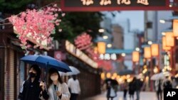 Orang-orang berjalan melalui jalan perbelanjaan di sepanjang kuil Sensoji yang terkenal di lingkungan Asakusa di Tokyo. (Foto: AP)