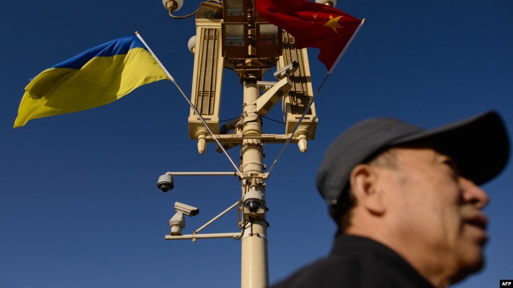 资料照：一名男子走过北京天安门广场灯柱上悬挂的中国与乌克兰国旗。（2013年12月5日）(photo:VOA)