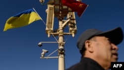 资料照：一名男子走过北京天安门广场灯柱上悬挂的中国与乌克兰国旗。（2013年12月5日）