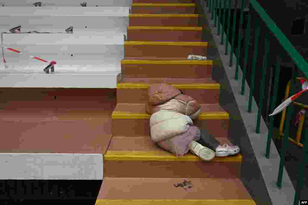 A child sleeps on steps while awaiting her mother at a COVID-19 testing center in Hong Kong as the city faces its worst coronavirus wave to date.