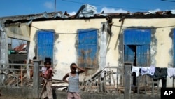 FILE — People stand outside a ruined home in Mananjary, Madagascar, Feb. 10, 2022. 