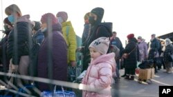 A little girl waits along with people crossing to Ukrainian government controlled areas from pro-Russian separatists controlled territory in Stanytsia Luhanska, the only crossing point open daily, in the Luhansk region, eastern Ukraine, Feb. 22, 2022.