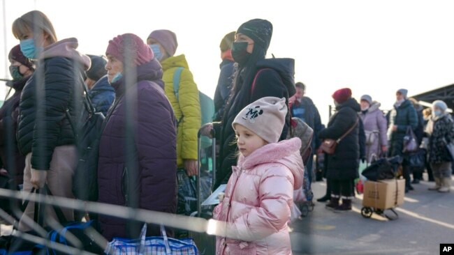 A little girl waits along with people crossing to Ukrainian government controlled areas from pro-Russian separatists controlled territory in Stanytsia Luhanska, the only crossing point open daily, in the Luhansk region, eastern Ukraine, Feb. 22, 2022.