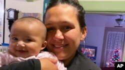 In this Dec. 2020, photo provided by Mary Risling, missing woman Emmilee Risling is seen holding her infant daughter at a home in California. The 33-year-old college graduate with ancestry from three tribes was last seen more than four months ago on the
